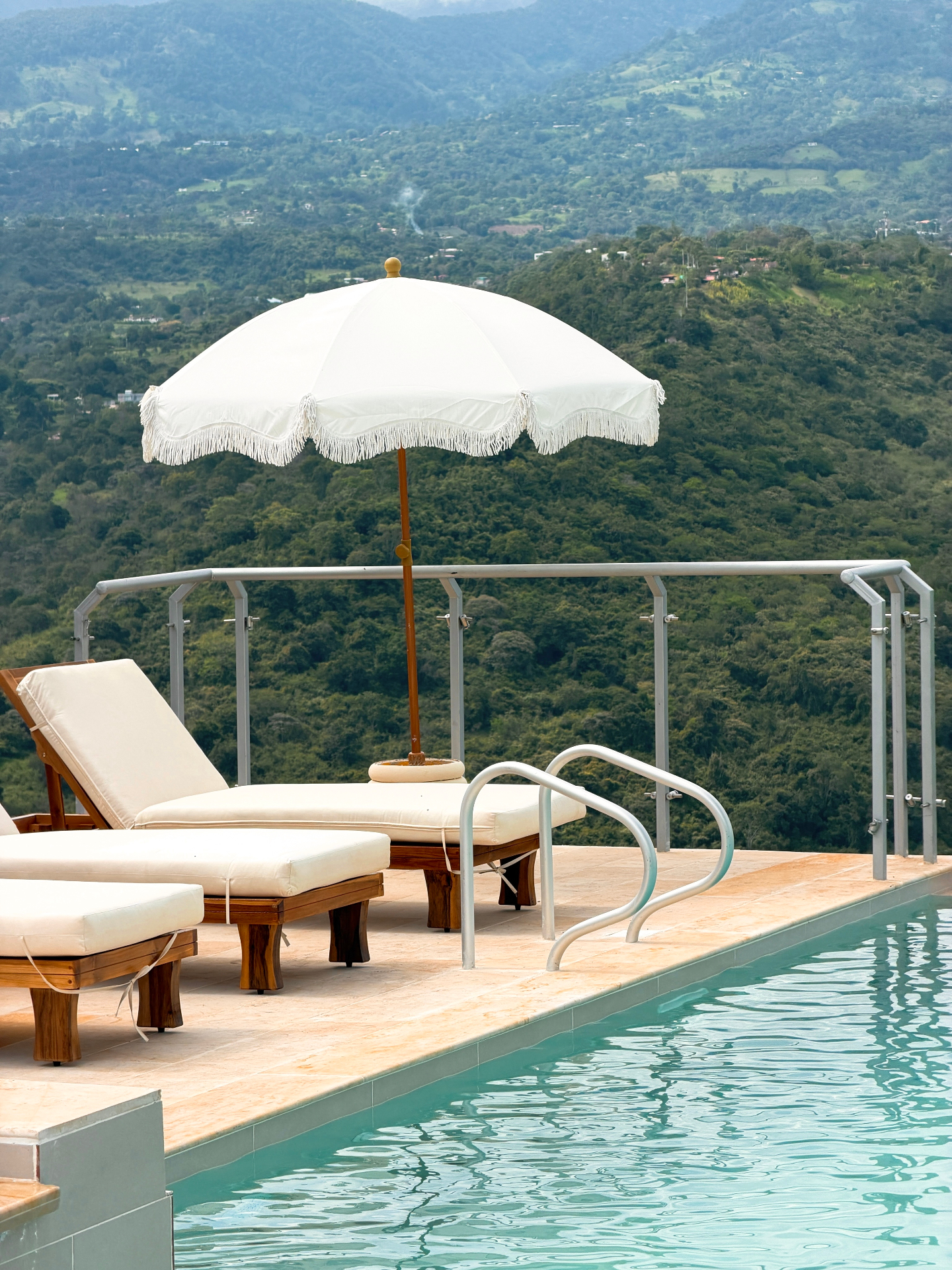 Terraza de la piscina con camastros y sombrilla